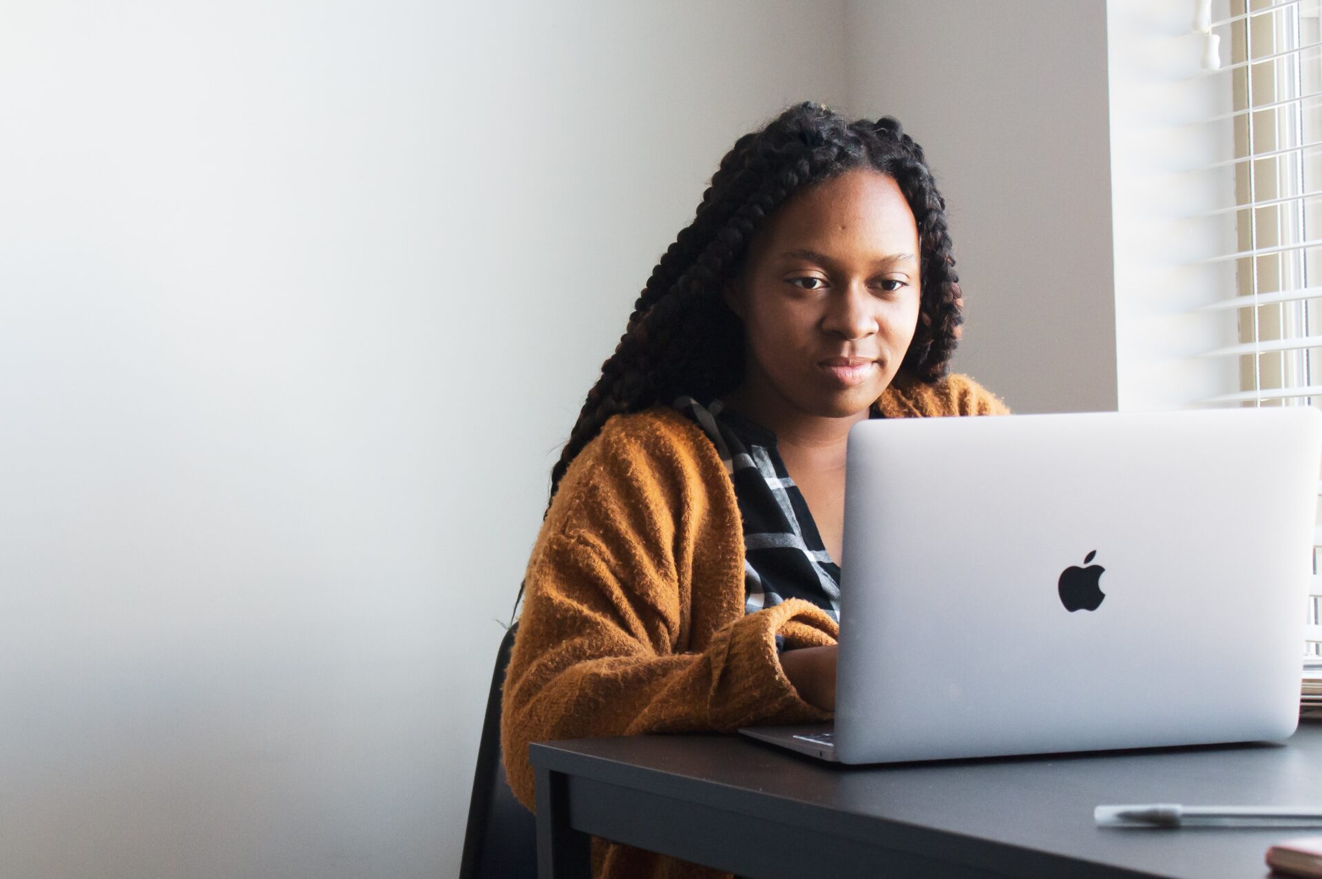 Female African student in a yellow cardigan typing on a laptop