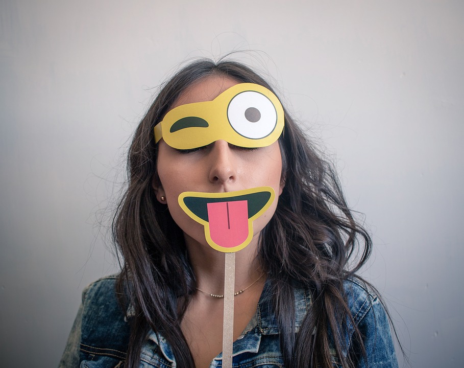 A woman holding emoji eyes and mouth over her face