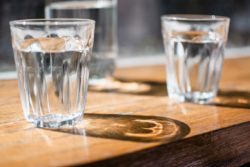 two short glasses of water on a timber table
