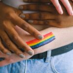 two hands of different nationalities holding each other with a rainbow painted on them 