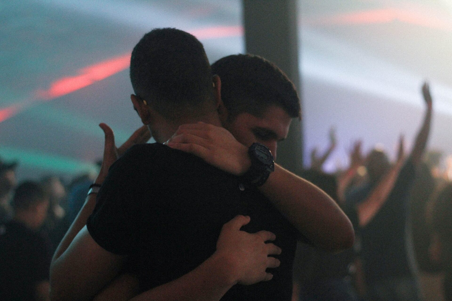 two men embracing in the crowd at a concert with confetti falling around them