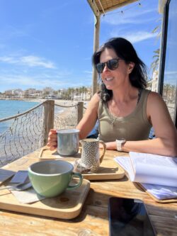 Katrina sits at a cafe looking over the spanish coastline