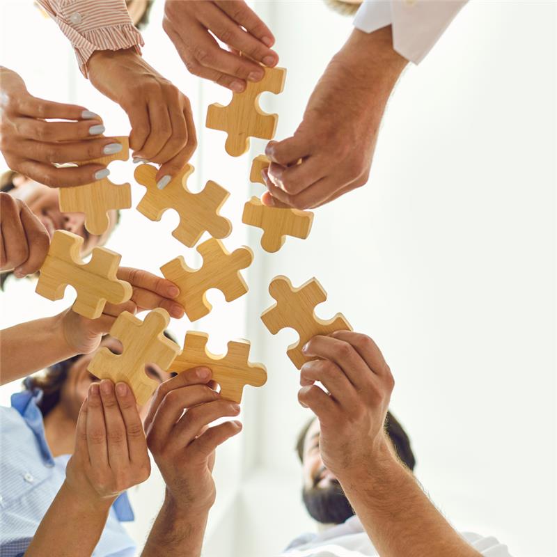 peoples hands holding puzzle pieces together in the air