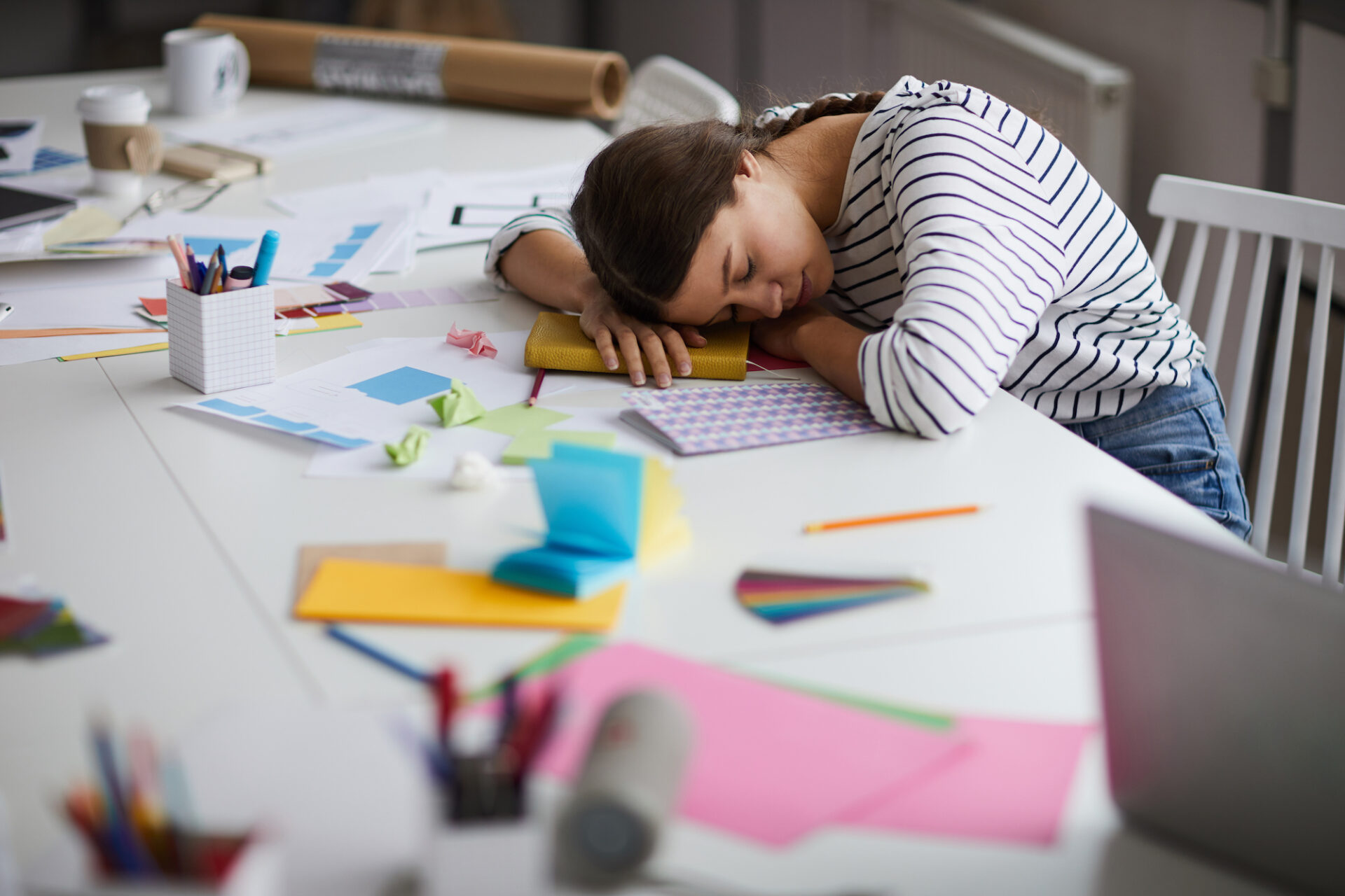 Side view portrait of young woman sleeping at desk exhausted from working or studying.